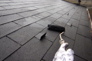 軍手をした手で屋根塗装をしている