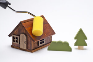 木製の家と木の模型にローラーで塗装するイメージ