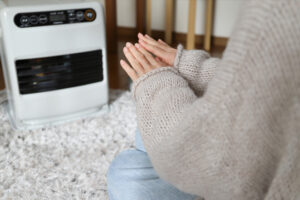 暖房で手を温める女性の手